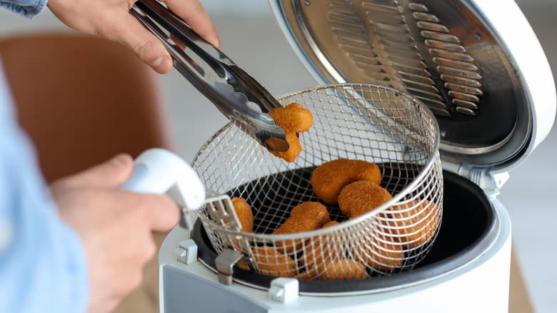 taking food from fryer with tongs