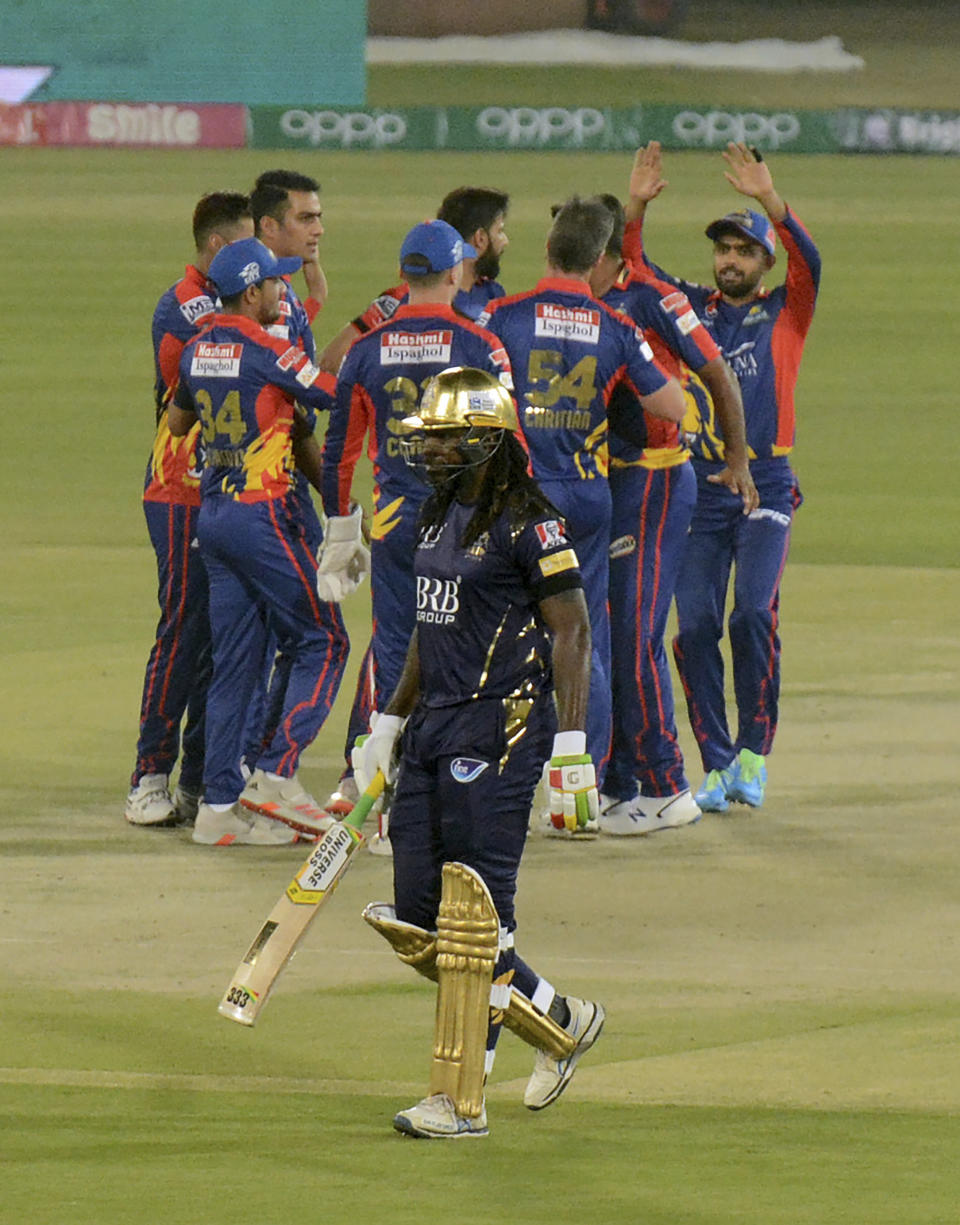 Quetta Gladiators Chris Gayle, front, walks back, while Karachi Kings players celebrate his dismissal during a Pakistan Super League T20 cricket match between Karachi Kings and Quetta Gladiators at National Stadium, in Karachi, Pakistan, Saturday, Feb. 20 2021. (AP Photo/Fareed Khan)