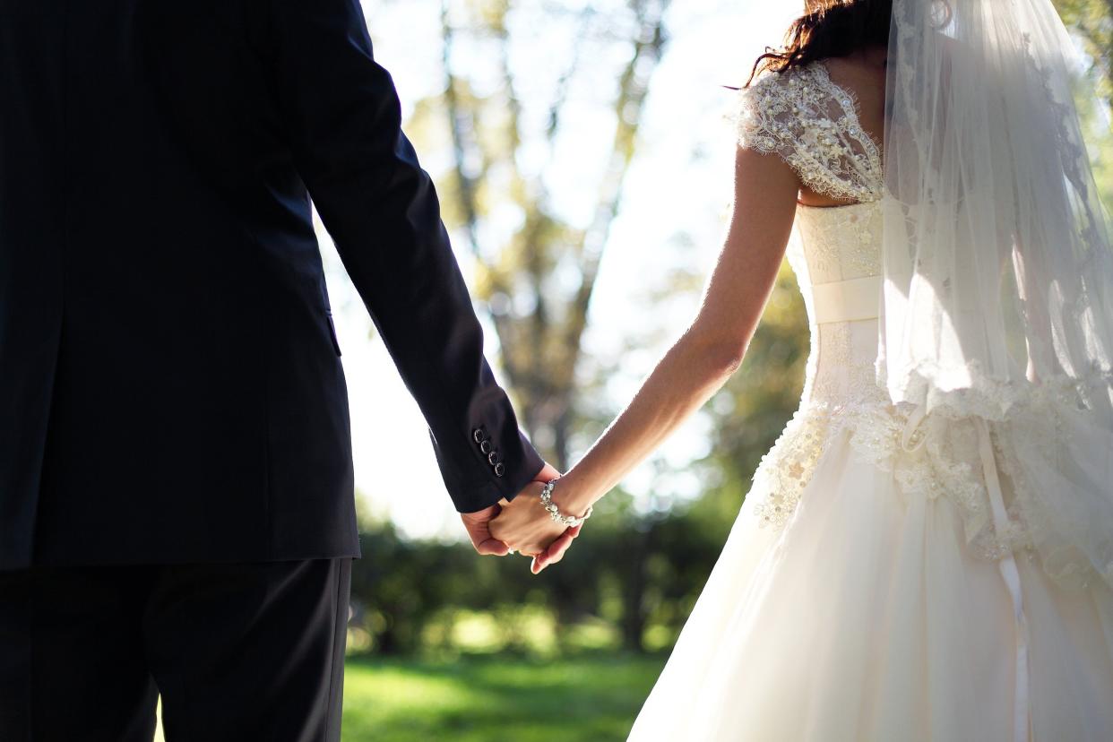 Close-up of newly married couple holding hands