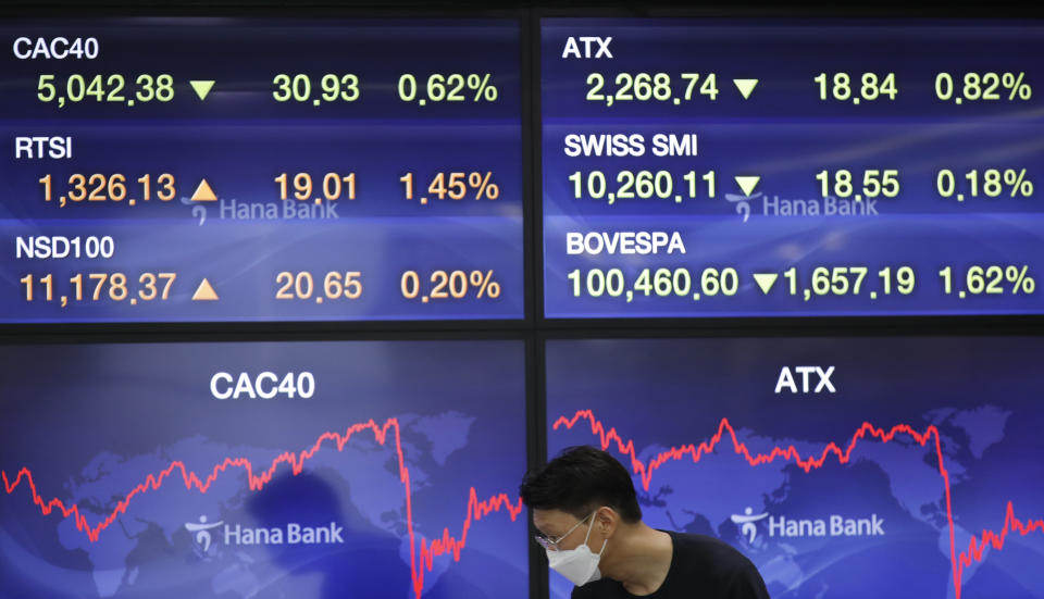 A currency trader stands near the screens at the foreign exchange dealing room in Seoul, South Korea, Friday, Aug. 14, 2020. Asian shares were mixed on Friday as investors studied fresh data out of China showing its recovery remains subdued. (AP Photo/Lee Jin-man)