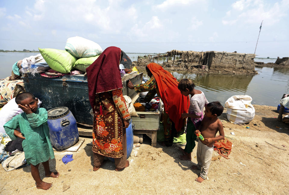 Women gather salvaged belongings from their flooded home after monsoon rains, in the Qambar Shahdadkot district of Sindh Province, of Pakistan, Tuesday, Sept. 6, 2022. More than 1,300 people have been killed and millions have lost their homes in flooding caused by unusually heavy monsoon rains in Pakistan this year that many experts have blamed on climate change. (AP Photo/Fareed Khan)