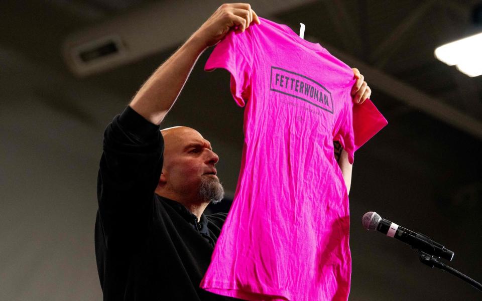 Fetterman holds up a "Fetterwoman" campaign shirt while delivering remarks during a "Women For Fetterman" rally at Montgomery County Community College in Blue Bell, Pennsylvania - AFP