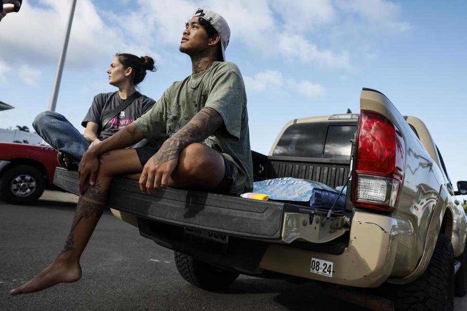 A woman and a man sit on the tailgate of a pickup truck