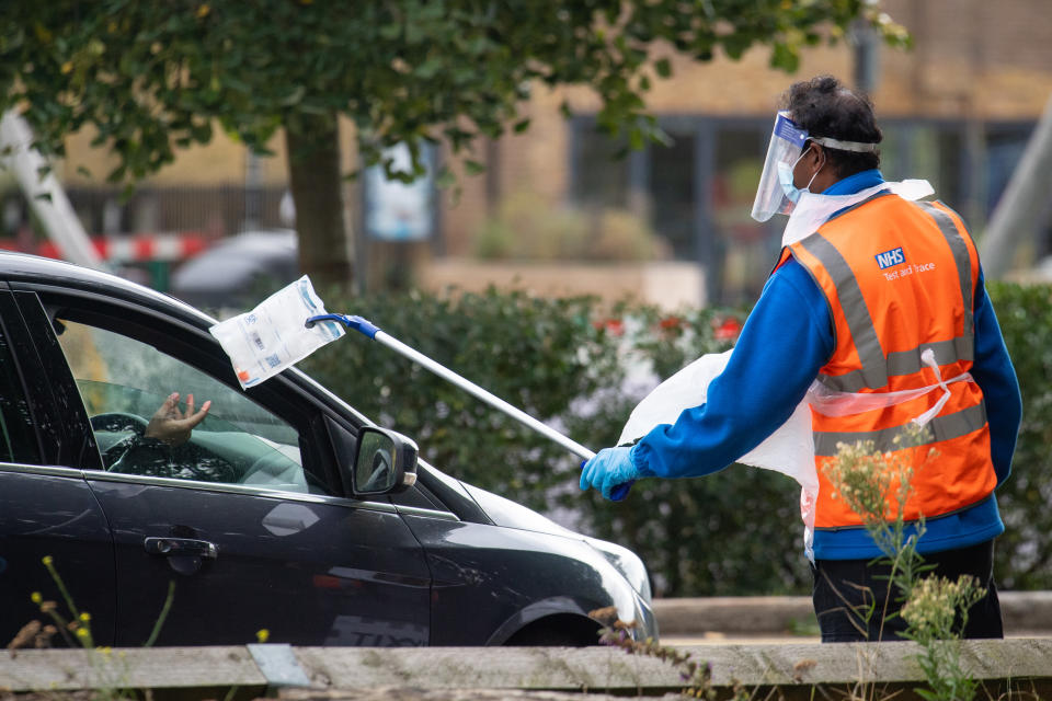 A member of staff collects a completed test kit from a visitor at a Covid-19 testing centre in Southwark, south London, after a range of new restrictions to combat the rise in coronavirus cases came into place in England. (Photo by Dominic Lipinski/PA Images via Getty Images)