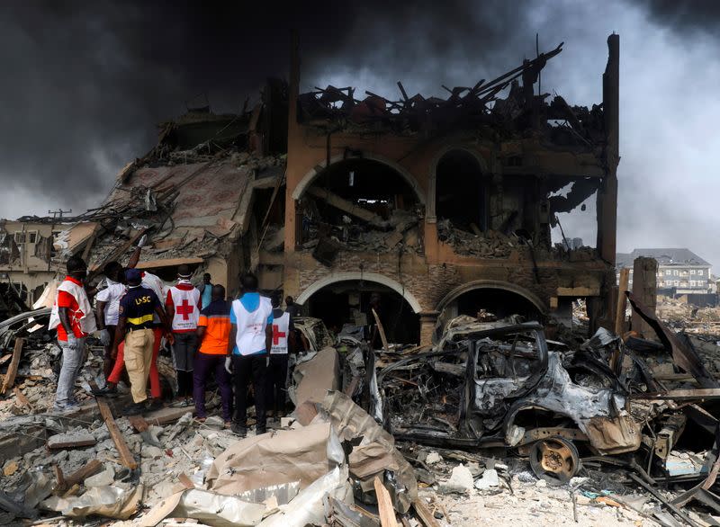 Paramedics and security men observe a building that was damaged by the pipeline explosion at Abule- Ado in Lagos