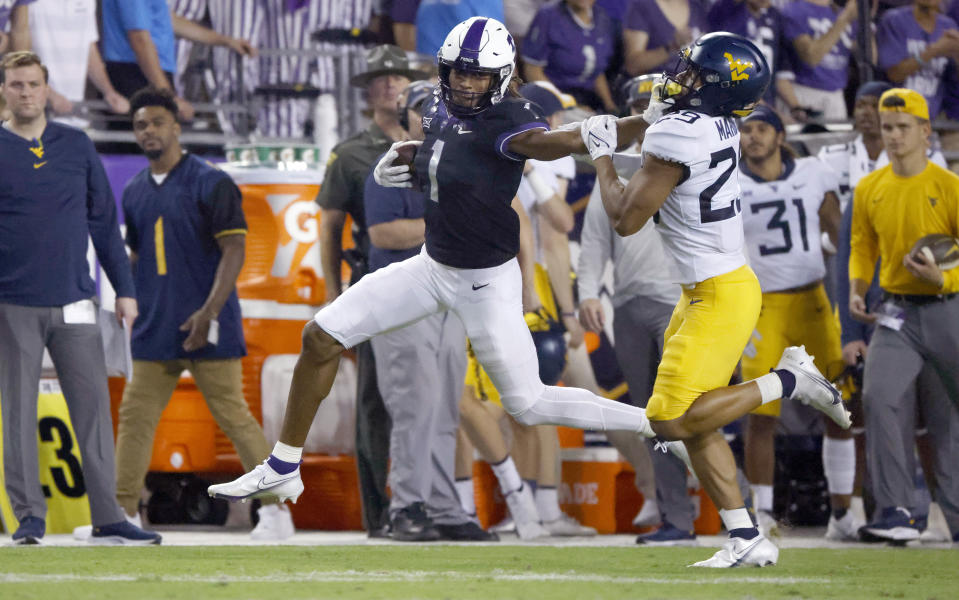 TCU wide receiver Quentin Johnston (1) stiff-arms West Virginia safety Sean Mahone (29) after making a catch for a first down during the first half of an NCAA college football game Saturday, Oct. 23, 2021, in Fort Worth, Texas. (AP Photo/Ron Jenkins)