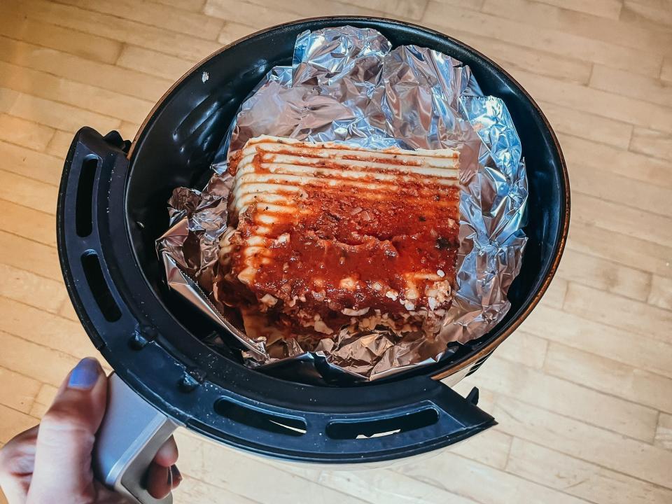 a square of lasagna in an air fryer basket