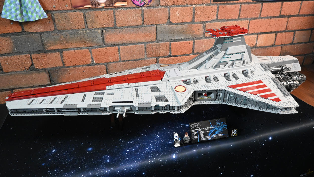  A side-on view of the Lego UCS Venator, sitting on a starry tabletop and framed against a brick wall. 