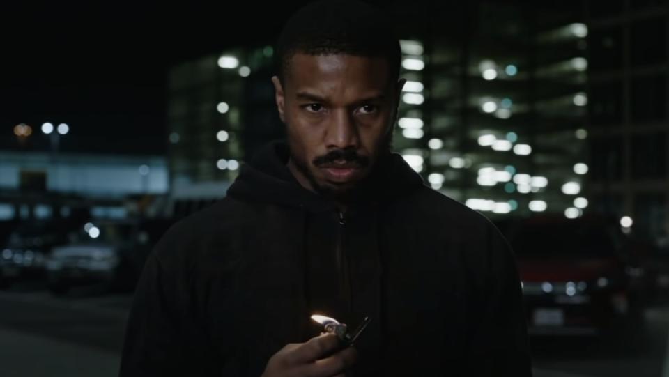 Michael B. Jordan wearing all black at night and holding a lighter that is lit in Amazon Prime Video's Without Remorse