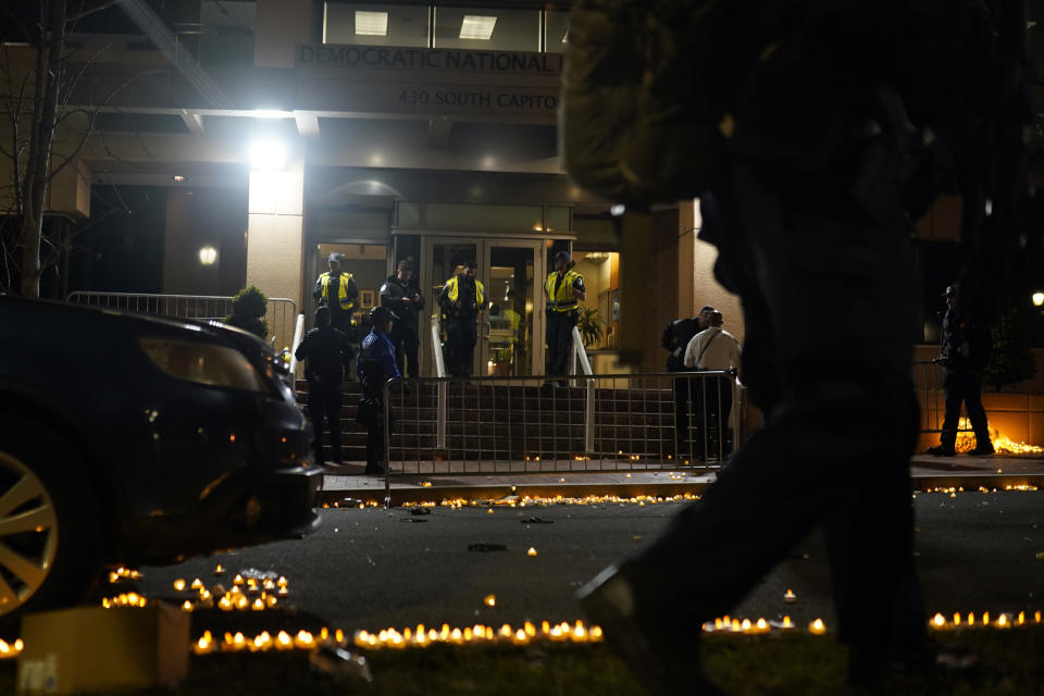 Candles lit by protesters line the street as U.S. Capitol Police officers stand outside the headquarters of the Democratic National Committee Wednesday, Nov. 15, 2023, in Washington. (AP Photo/Nathan Howard)