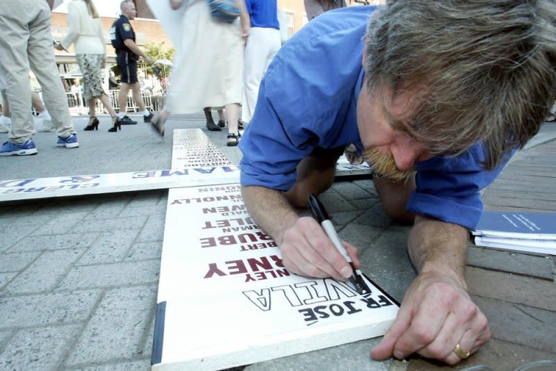 A protester adds the name of a defrocked priest to the top of the "Cross of Shame" on July 30, 2003, outside the Cathedral of the Holy Cross in Boston. On July 23, 2003, the Massachusetts attorney general said an investigation indicated nearly 1,000 cases of abuse by Roman Catholic priests and other church personnel in the Boston diocese over 60 years. File Photo by Steven E. Frischling/UPI