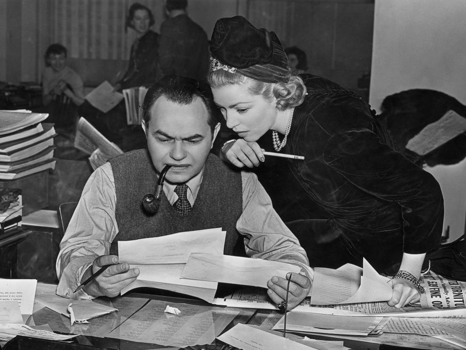 American actors Edward G. Robinson (Emanuel Goldenberg, 1893 - 1973) and Claire Trevor (1909 - 2000) review important documents over a news room desk, in a promotional portrait for the radio program.