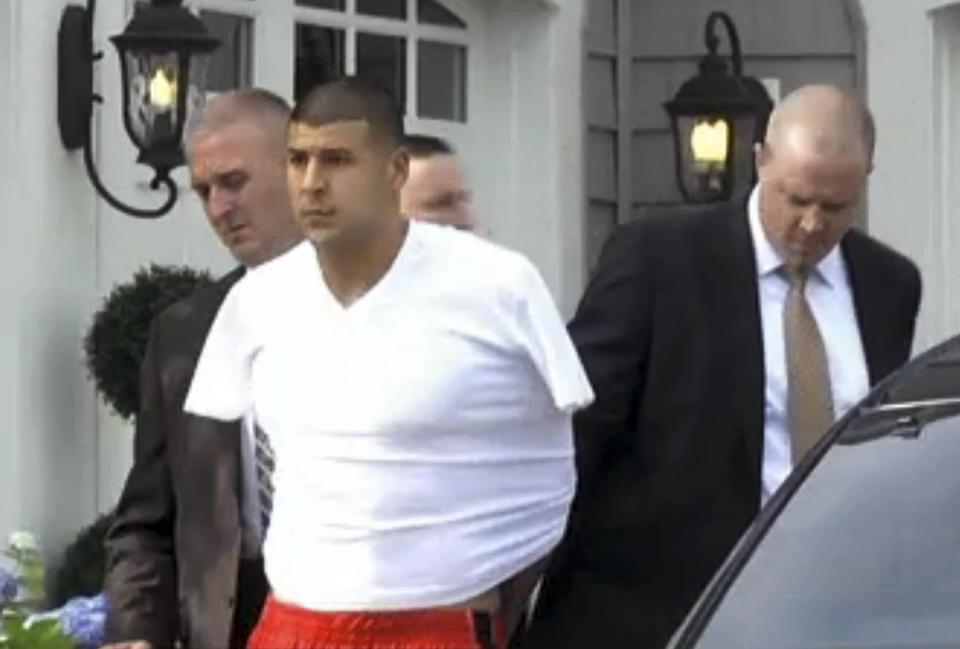 Police escort Aaron Hernandez from his home in handcuffs in 2013. (AP)