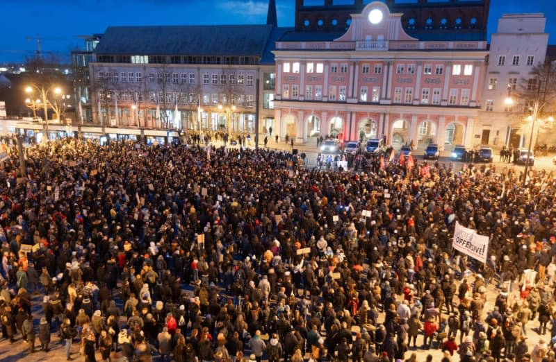 People hold placards during a demonstration against right-wing extremism under the slogan "Never again is now - all together against fascism" on the Neuer Markt in front of the town hall. Jens Büttner/dpa