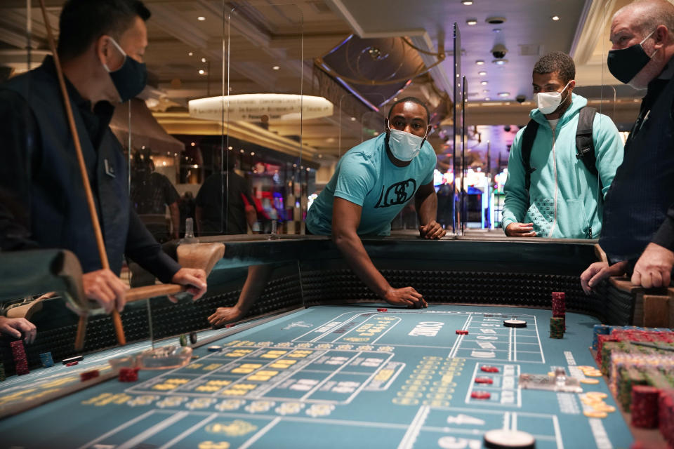 People play craps after the reopening of the Bellagio hotel and casino Thursday, June 4, 2020, in Las Vegas. Casinos in Nevada were allowed to reopen on Thursday for the first time after temporary closures as a precaution against the coronavirus. (AP Photo/John Locher)