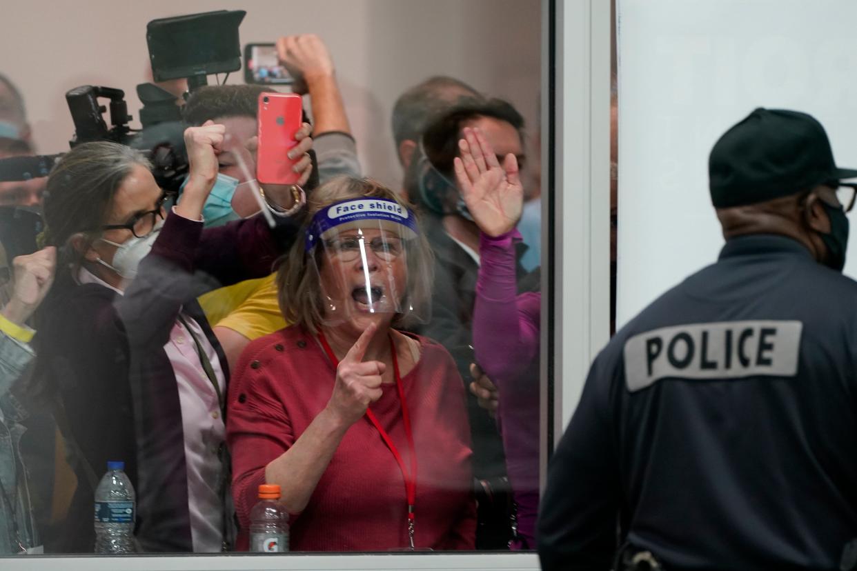 Election challengers yell as they look through the windows of the central counting board as police were helping to keep additional challengers from entering due to overcrowding, in Detroit, on November 4, 2020 (AP)