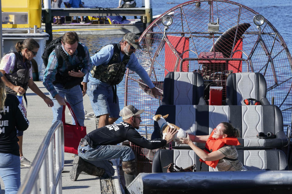 A Sanibel Island resident hands off her dog to rescuers from Project DYNAMO after she was rescued and transported to Fort Myers on Sept. 30, 2022. / Credit: Steve Helber / AP