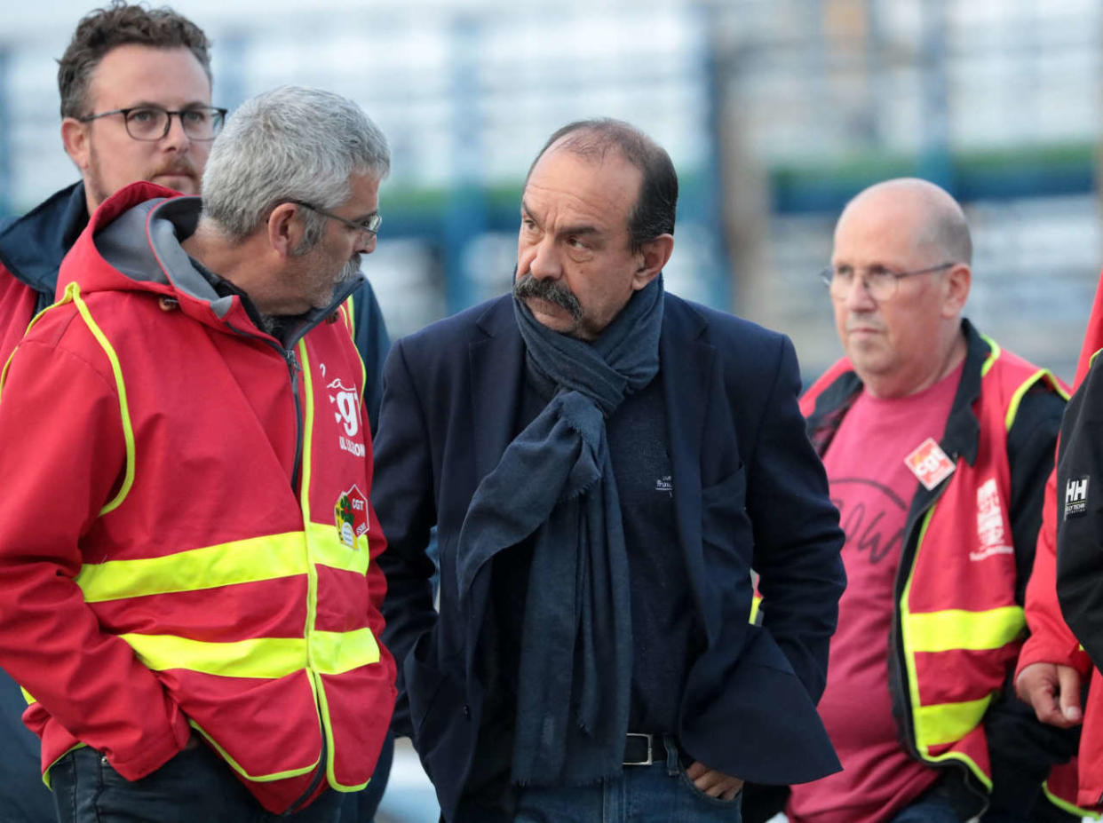 CGT Union leader Philippe Martinez (C) walks with striking workers at The Gravenchon Port-Jerome refinery, owned by US giant Esso-ExxonMobil, at Port-Jerome, northern France on October 12, 2022. - Striking French oil refinery employees have voted to maintain blockades now in their third week, despite a government order for some of them to return to work in a bid to get fuel supplies flowing. The industrial action to demand pay hikes has paralysed six out of the seven fuel refineries in France, leading to shortages of petrol and diesel exacerbated by panic-buying from drivers. (Photo by Lou BENOIST / AFP)