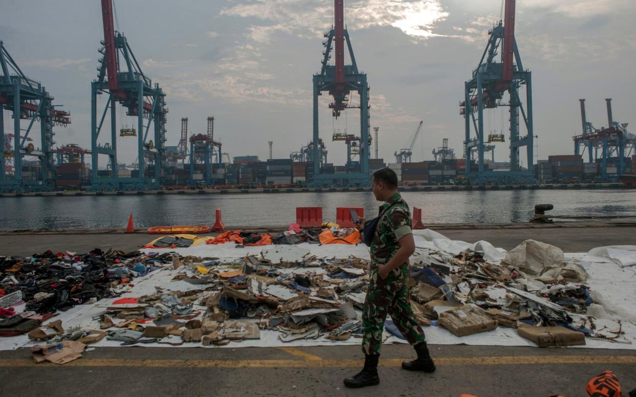 An Indonesian soldiers walk past debris retrieved from the waters where Lion Air flight JT 610 is believed to have crashed - AP