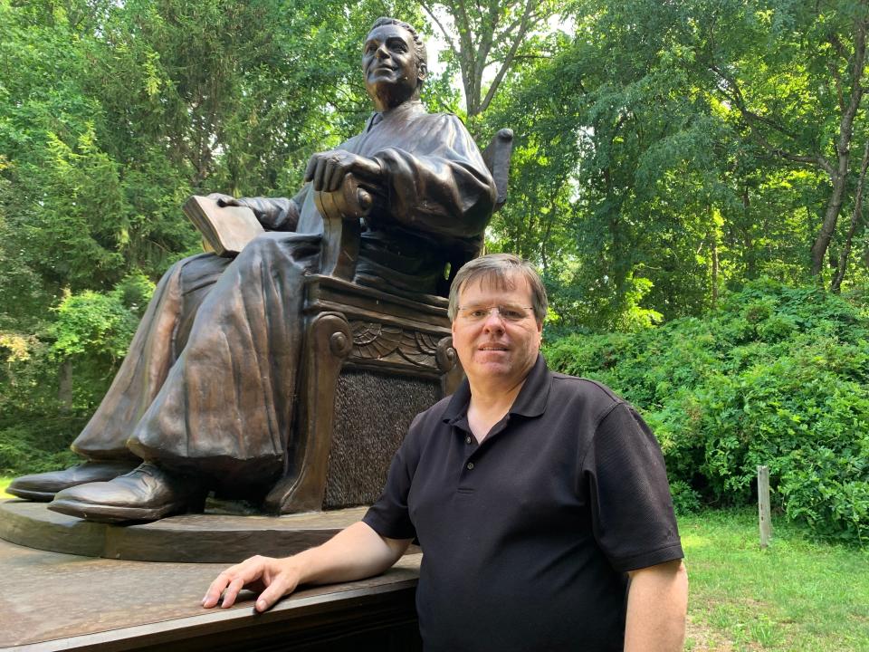 Toby Mendez and his statue of Judge Frank Cicone in his backyard sculpture garden.