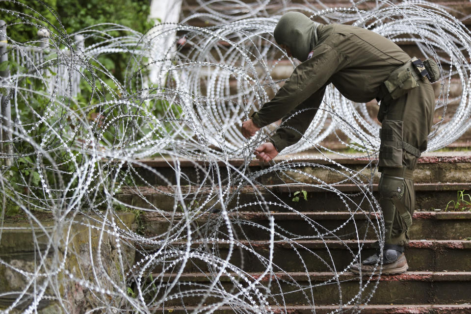 KFOR soldiers place a barbed wire in front of the city hall in the town of Zvecan, northern Kosovo, Wednesday, May 31, 2023. Hundreds of ethnic Serbs began gathering in front of the city hall in their repeated efforts to take over the offices of one of the municipalities where ethnic Albanian mayors took up their posts last week. (AP Photo/Bojan Slavkovic)