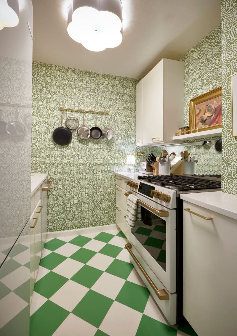 Wallpapered kitchen with white cabinets and appliances and green and white checkered floor.