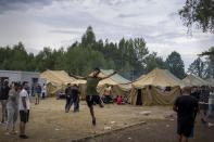 A migrant jumps as other walk inside the newly built refugee camp in the Rudninkai military training ground, some 38km (23,6 miles) south from Vilnius, Lithuania, Wednesday, Aug. 4, 2021. The Red Cross warned Wednesday that Lithuania's decision to turn away immigrants attempting to cross in from neighboring Belarus does not comply with international law. Lithuania, a member of the European Union, has faced a surge of mostly Iraqi migrants in the past few months. Some 4,090 migrants, most of them from Iraq, have crossed this year from Belarus into Lithuania. (AP Photo/Mindaugas Kulbis)