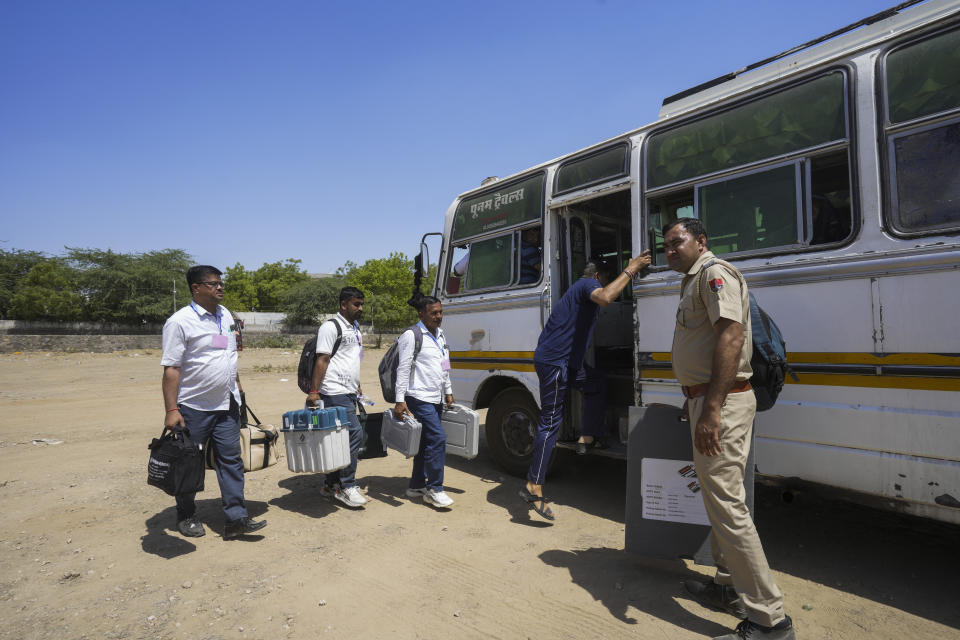 Officials carrying electronic voting machines walk to board their vehicles as they head to their assigned polling stations on the eve of the second phase of national elections at Barmer, Rajasthan, India, Thursday, April 25, 2024. (AP Photo/ Deepak Sharma)