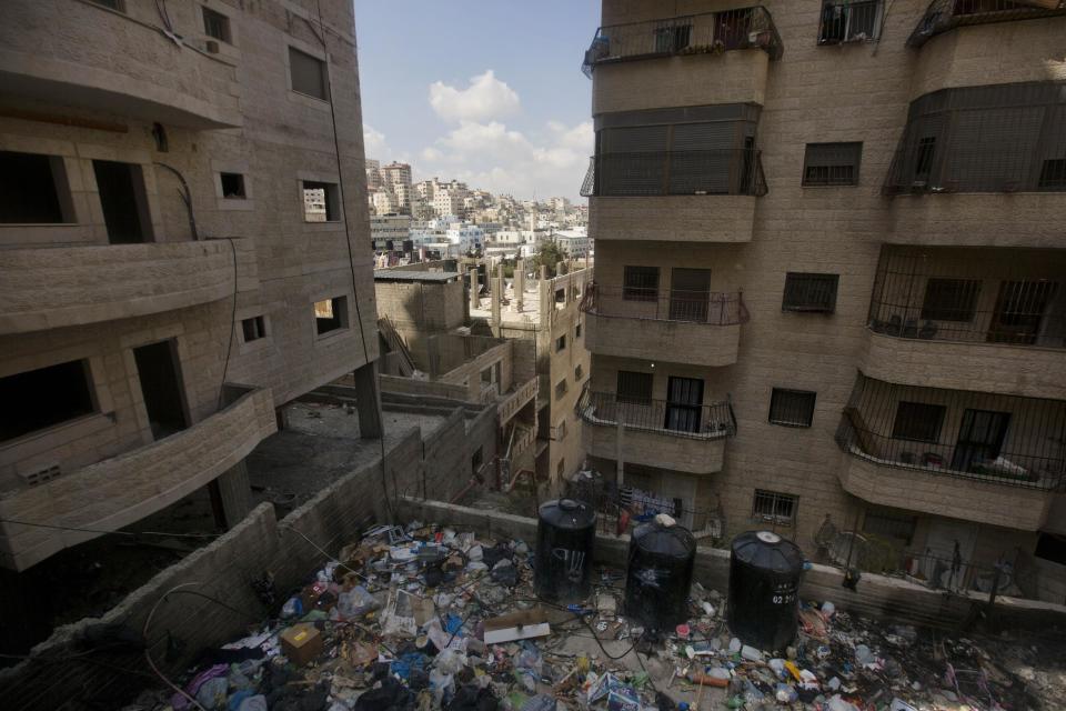 In this April 3, 2014 photo, water tanks are seen in between garbage near buildings in Shuafat, east Jerusalem. Tens of thousands of Palestinians in east Jerusalem have been without water for more than a month, victims of a decrepit and overwhelmed infrastructure and caught in a legal no-man’s land. Their district is technically part of Jerusalem municipality, but on the other side of the massive Israeli-built West Bank separation barrier, so Israeli services there are sparse yet Palestinian officials are barred for operating. With the scorching summer approaching, residents are growing increasingly desperate. (AP Photo/Sebastian Scheiner)