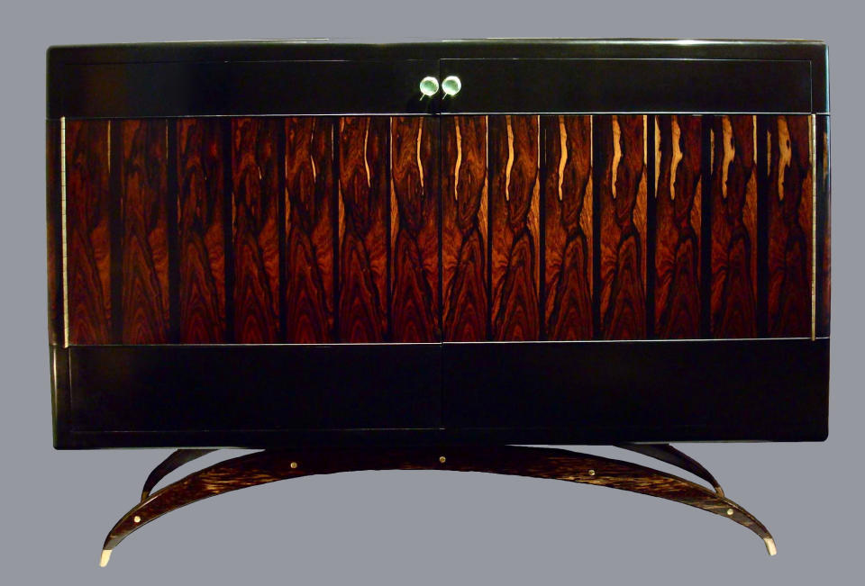 This publicity product image provided by BespokeGlobal.com shows a Bespoke Global Lacquered Crab Cabinet by Antoine Schapira. Artisanship meets whimsy in Shapira’s two-door Brazilian rosewood lacquered cabinet. The "body" of the crab is fashioned from lacquered Brazilian rosewood, enhanced with arching cast brass "legs" wrapped with palm wood. Luxe finishes like lacquer and metallics are on trend this fall. (AP Photo/BespokeGlobal.com)