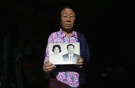 Ok Chul-soon, 82, whose husband was abducted in 1972 by North Koreans and captain of Jeon's fishing boat, poses for photographs with a picture of her (L) and her husband at her house in Nongso village in Geoje, about 470 km (292 miles) southeast of Seoul October 29, 2013. REUTERS/Kim Hong-Ji