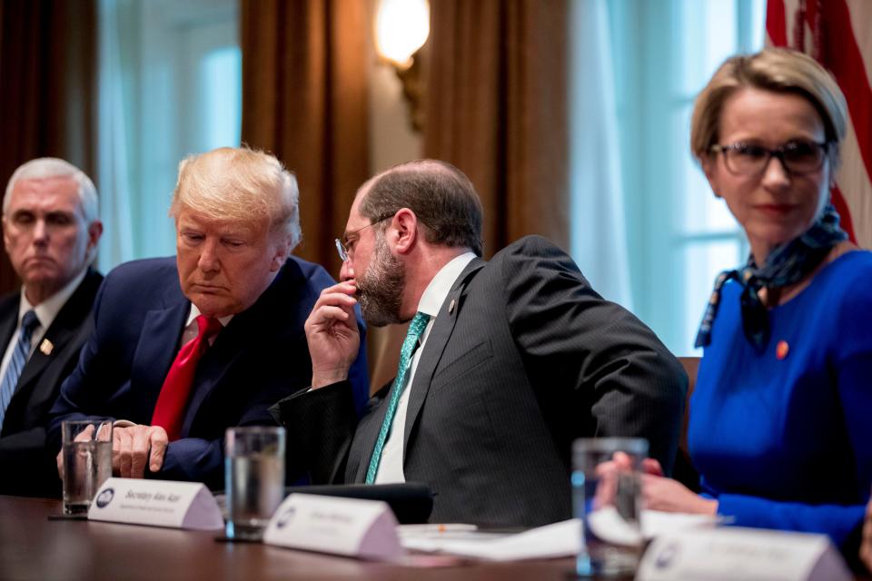 Health and Human Services Secretary Alex Azar, center, accompanied by Vice President Mike Pence, left, whispers with President Donald Trump, during a meeting with pharmaceutical executives on the coronavirus.