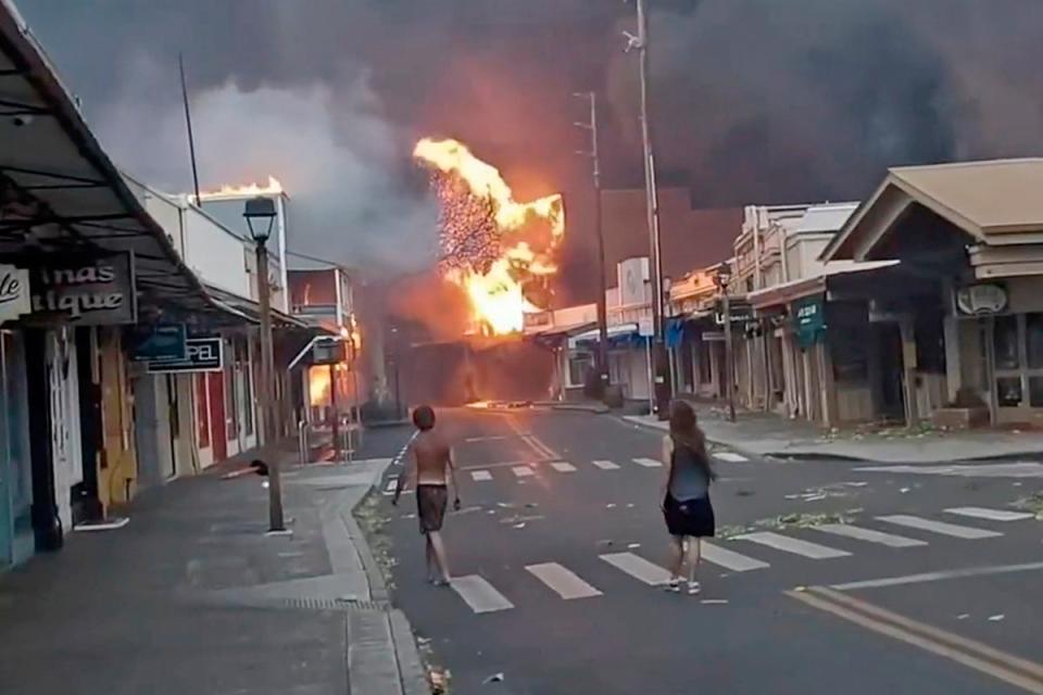 People watch as smoke and flames fill the air from raging wildfires on Front Street in downtown Lahaina (AP)