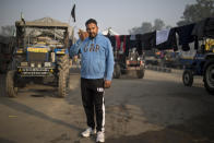 Hardeep Singh, 42, stands for a photograph next to his tractor trailer parked on a highway as he joins tens of thousands of protesting farmers for a protest against new farm laws at the Delhi-Haryana state border, India, Tuesday, Dec. 1, 2020. The protests started in September but drew nationwide attention last week when the farmers marched from northern Punjab and Haryana, two of India's largest agricultural states. Their rallying call is “Inquilab Zindabad” (“Long live the revolution”). (AP Photo/Altaf Qadri)