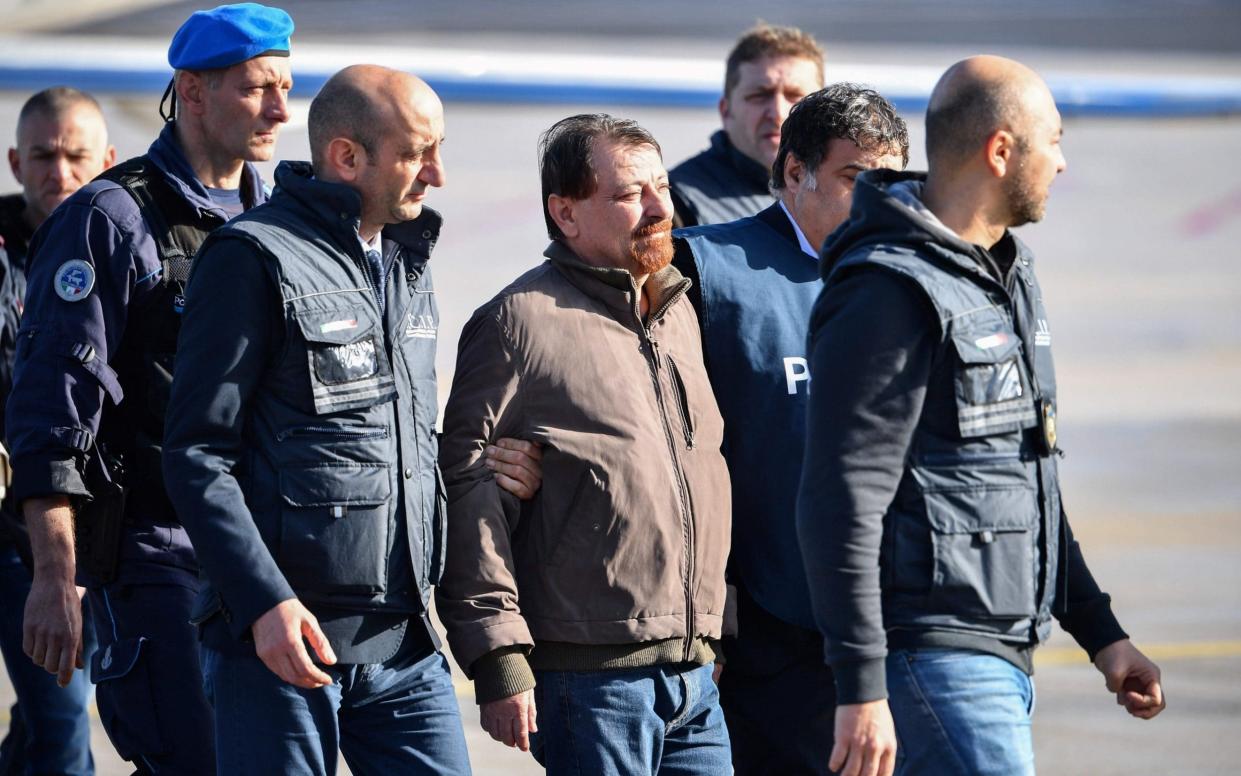 Former communist militant Cesare Battisti is escorted by Italian police after stepping off a plane from Bolivia  - AFP