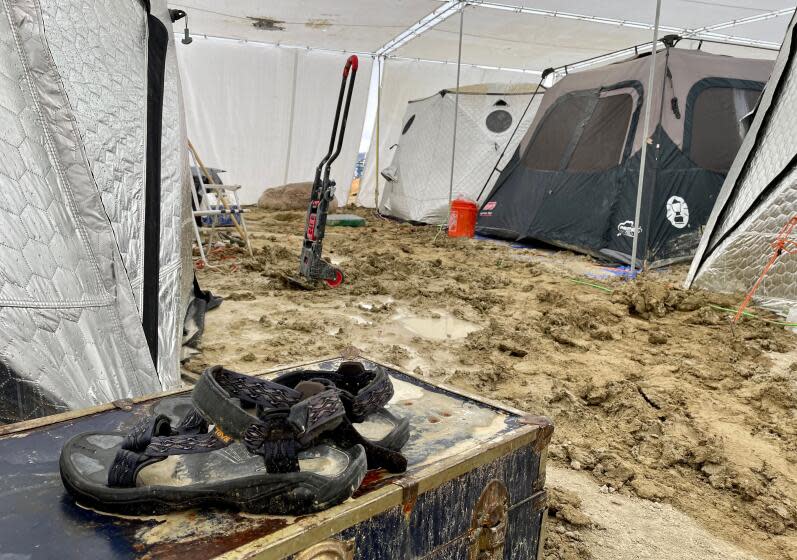 A pair of Teva sandals are seen on a chest in the middle of tents sitting in a muddy desert plain on September 3, 2023, after heavy rains turned the annual Burning Man festival site in Nevada's Black Rock desert into a mud pit. Tens of thousands of festivalgoers were stranded September 3, in deep mud in the Nevada desert after rain turned the annual Burning Man gathering into a quagmire, with police investigating one death. Video footage showed costume-wearing "burners" struggling across the wet gray-brown site, some using trash bags as makeshift boots, while many vehicles were stuck in the sludge. (Photo by Julie JAMMOT / AFP) (Photo by JULIE JAMMOT/AFP via Getty Images)