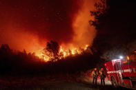 Firefighters watch the Bear Fire approach in Oroville, Calif., on Wednesday, Sept. 9, 2020. The blaze, part of the lightning-sparked North Complex, expanded at a critical rate of spread as winds buffeted the region.They work 50 hours at a stretch and sleep on gymnasium floors. Exploding trees shower them with embers. They lose track of time when the sun is blotted out by smoke, and they sometimes have to run for their lives from advancing flames. Firefighters trying to contain the massive wildfires in Oregon, California and Washington state are constantly on the verge of exhaustion as they try to save suburban houses, including some in their own neighborhoods. (AP Photo/Noah Berger)