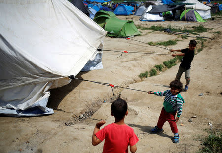 Children help their father fix their tent at a makeshift camp for migrants and refugees at the Greek-Macedonian border near the village of Idomeni, Greece, April 22, 2016. REUTERS/Stoyan Nenov