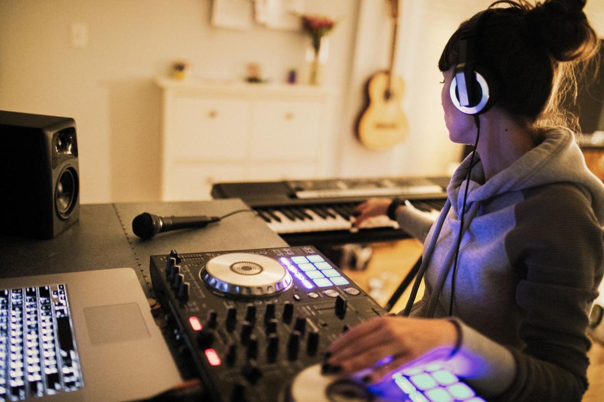 young woman making music with computer at home