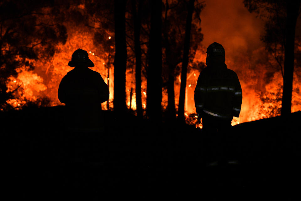 Pictured are two silhouettes of firefighters in front of bushfires in NSW. 