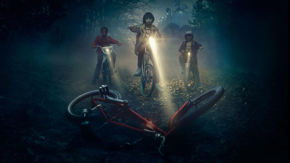 Three boys on bicycles shining lights on a downed bicycle, from the first season of Stranger Things.