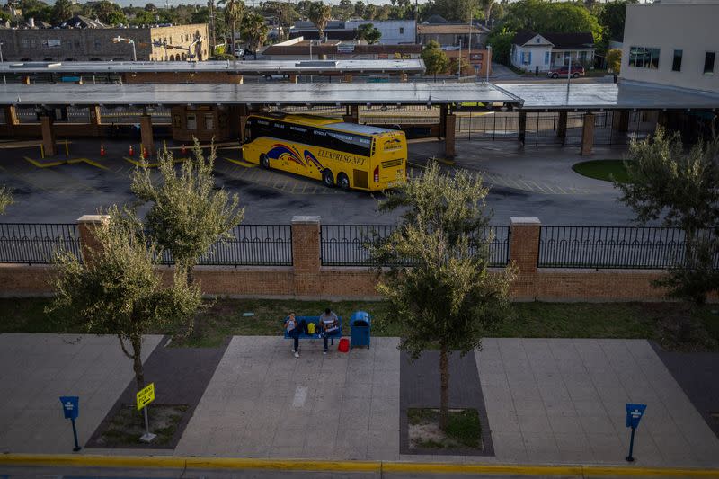 José Manuel (izquierda), un solicitante de asilo venezolano, se sienta en un banco mientras espera la salida de un autobús a Chicago, fuera de un centro de procesamiento de migrantes en el centro de Brownsville, Texas