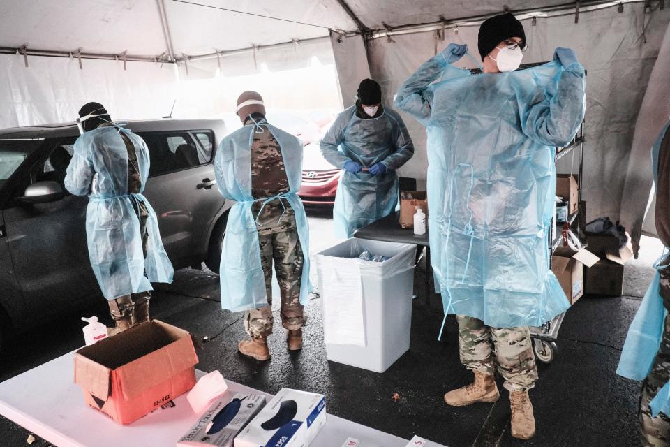 Members of the Ohio National Guard put on protective equipment as they prepare to administer coronavirus tests at a drive-thru site Jan. 5 in Akron, Ohio. In response to the surge of the omicron variant, Ohio Gov. Mike DeWine deployed the National Guard to assist medical personnel in health facilities and testing sites.