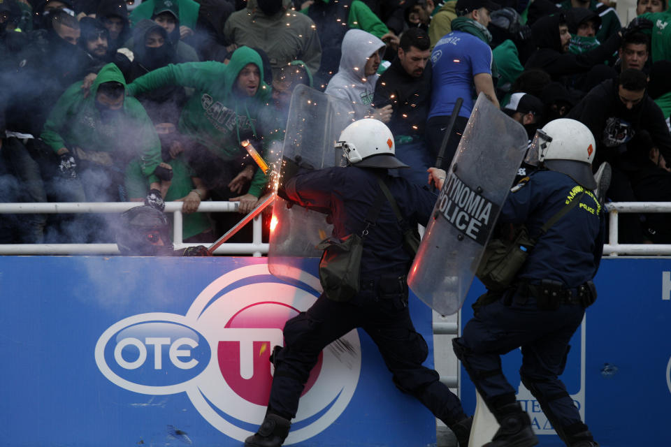 Riot policemen clash with fans prior to the cup final between Athens's Panathinaikos and Thessalonikis's PAOK at the Olympic Stadium in Athens, Greece Saturday, April 26 2014. More than 300 buses carrying PAOK supporters from the northern Greek city of Thessaloniki were stopped by police at a toll station 34 kilometers (21 miles) north of the capital Athens. The supporters were searched and allowed to proceed, 20 buses at a time, to the Athens Olympic Stadium, where the Greek Cup final between soccer clubs PAOK and Panathinaikos is taking place. Police, fearing clashes between rival fans, has been directing supporters to different gates of the stadium several hours before the game's start at 8 p.m. local(AP Photo/Kostas Tsironis)