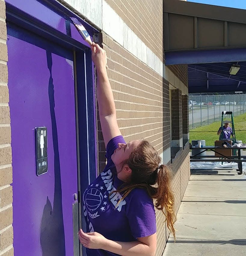 Volunteer Bailey Ledbetter helps paint the concession stand at North Henderson High’s football field as part of Day of Action in Henderson County in August 2019.