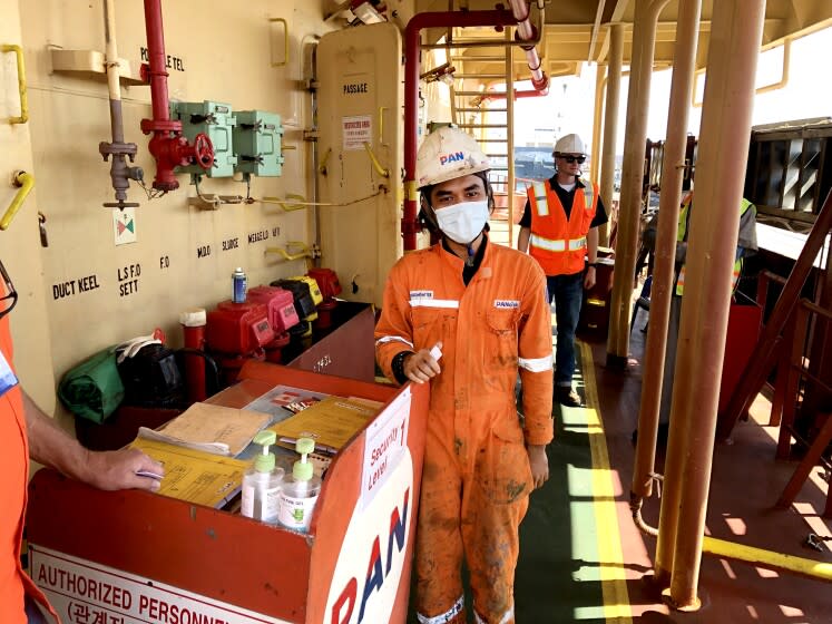 LONG BEACH, CALIF., OCT. 14, 2021: Twenty-four year-old Indonesian seafarer Abrorizki Geraldy Aulia, in the foreground, served as a crew member of the Southern Korean flagged bulk cargo ship Pan Amber for 15 months without a break as the pandemic raged and helped slow the global supply chain of goods movement to a crawl. (Ronald D. White / Los Angeles Times)