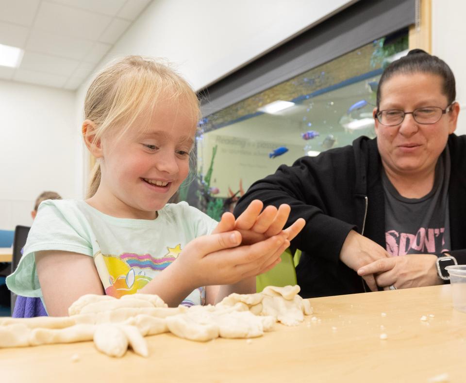 Aryiah Lash, 7, makes a bird with unicorn horn, shark fins and flamingo legs with clay as her mother Kathy Lash looks on at the Perry Sippo Branch Library's Trail Tales/Arctic Animal Legends story and a craft program.
