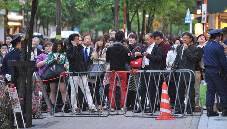 Pedestrians gather to watch visiting US President Barack Obama arrive Sukiyabashi Jiro restaurant in Tokyo on April 23, 2014