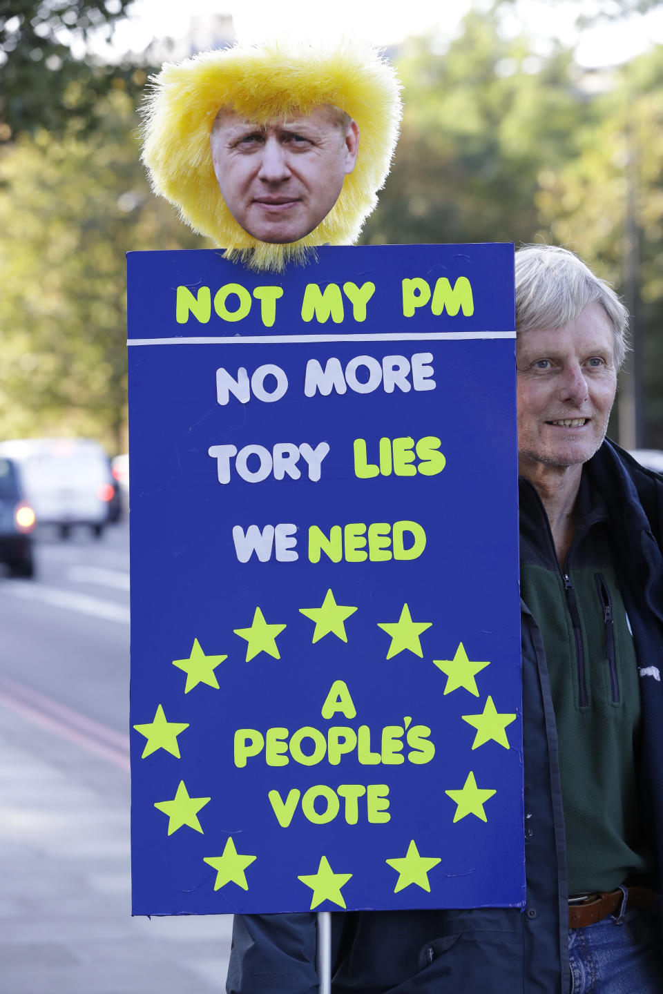 An anti-Brexit supporters holds a sign with a picture of Britain's Prime Minister Boris Johnson near the Houses of Parliament in London, Saturday, Oct. 19, 2019. Britain's Parliament is set to vote in a rare Saturday sitting on Johnson's new deal with the European Union, a decisive moment in the prolonged bid to end the Brexit stalemate. Various scenarios may be put in motion by the vote. (AP Photo/Kirsty Wigglesworth)