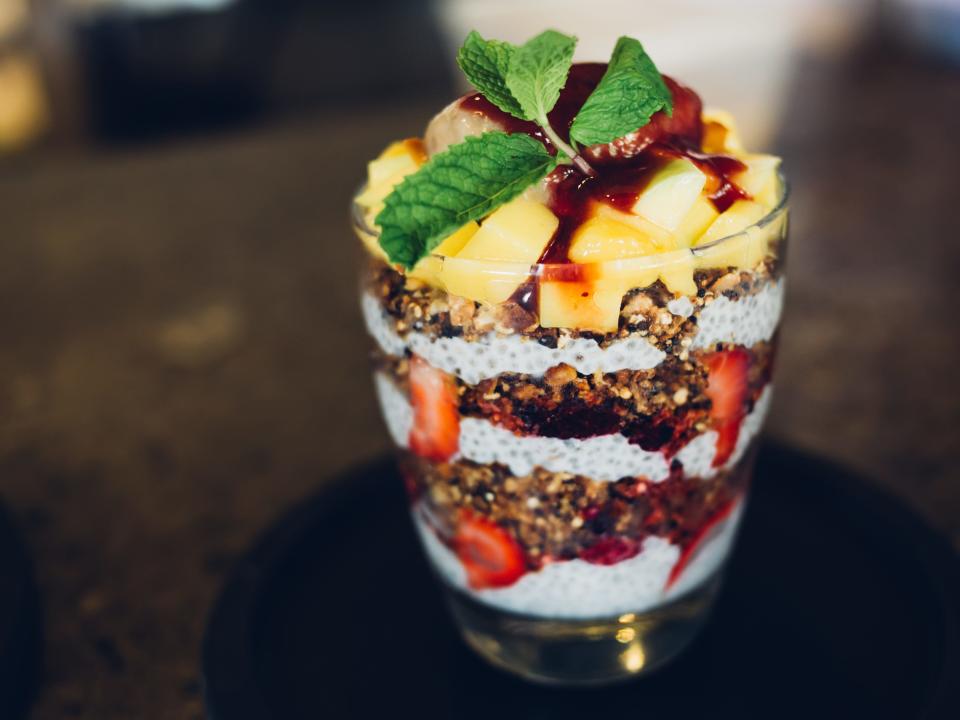 yogurt parfait with chia seeds, topped with mint in a glass cup